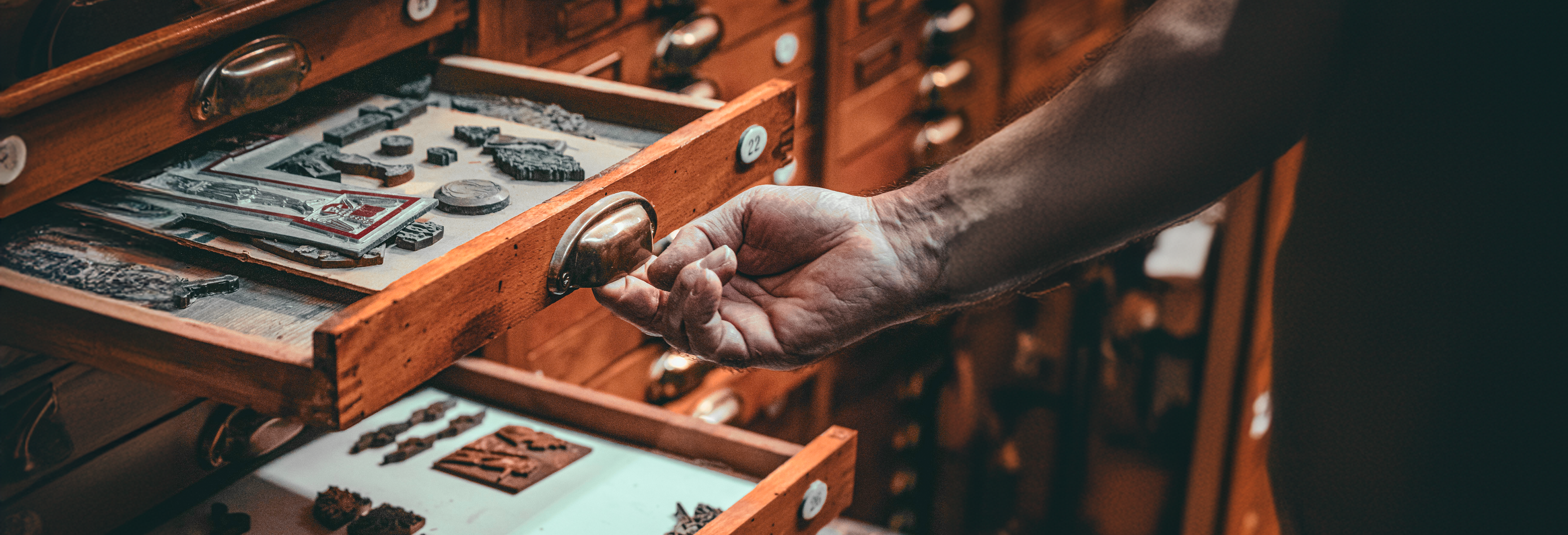 Masculine hand pulling out drawers with cultural objects. Photo by Mikita Yo on Pexels.