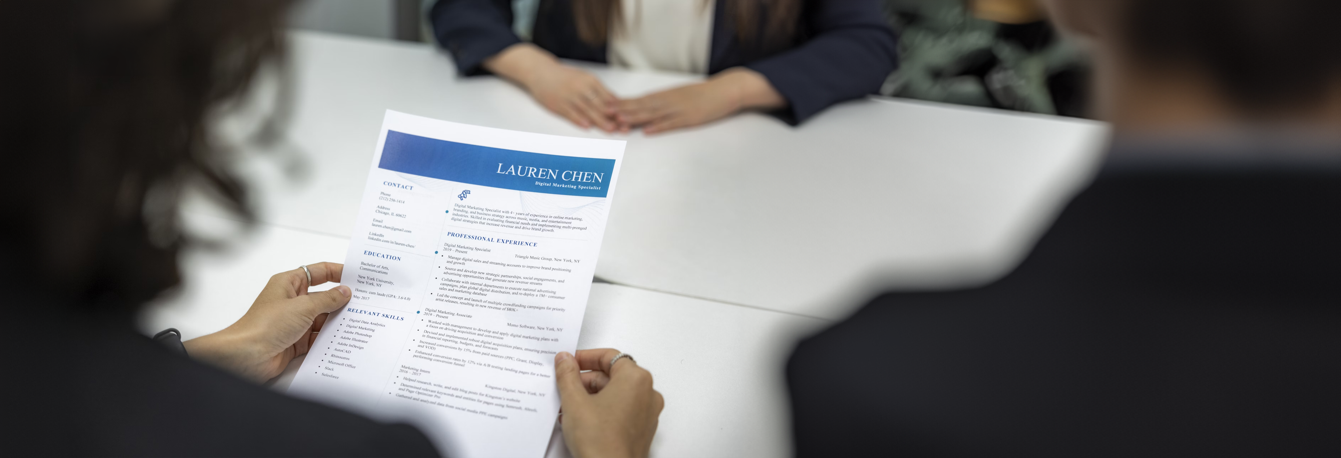 Woman holding a CV sitting opposite another person.