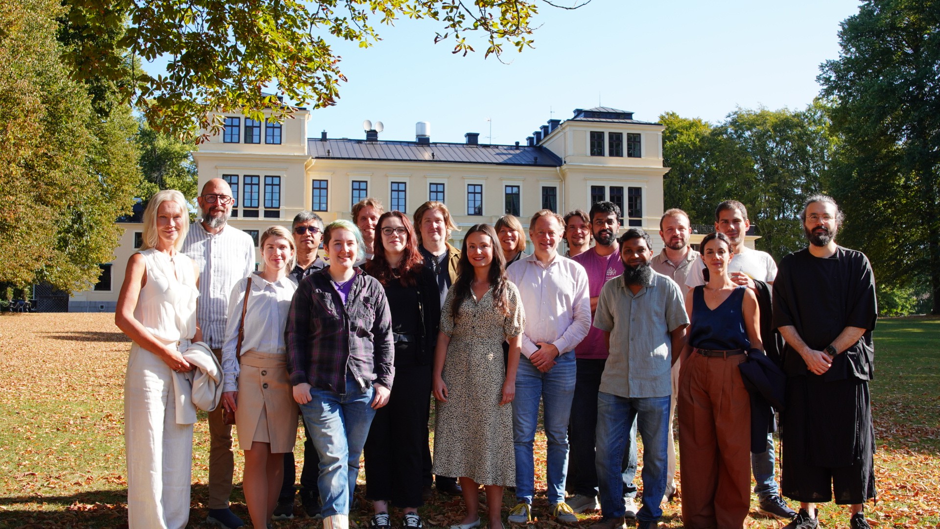 Group of happy people smiling in front of a white Swedish castle.
